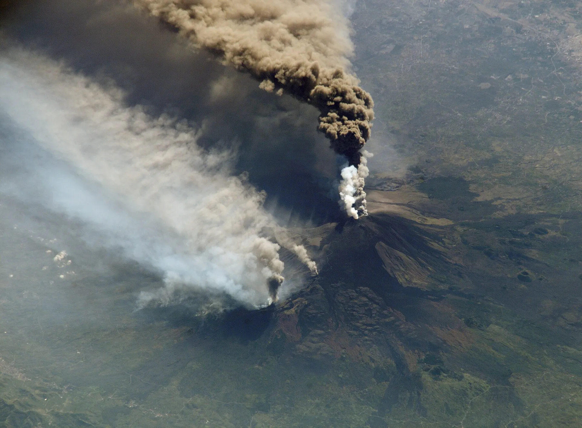 Ash plume rising from Mount Etna above the Sicilian countryside