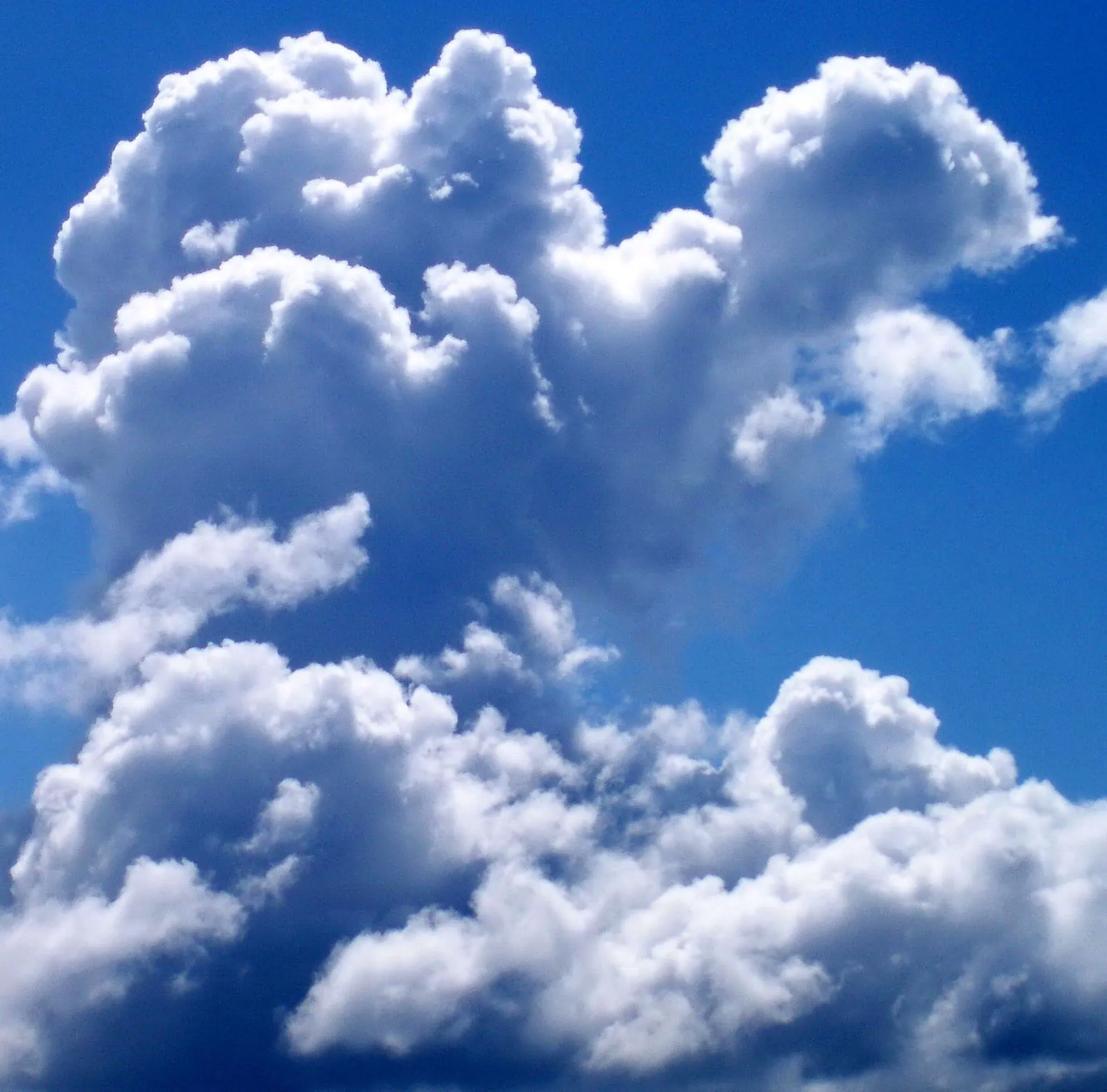 Towering white cumulus clouds against a deep blue sky