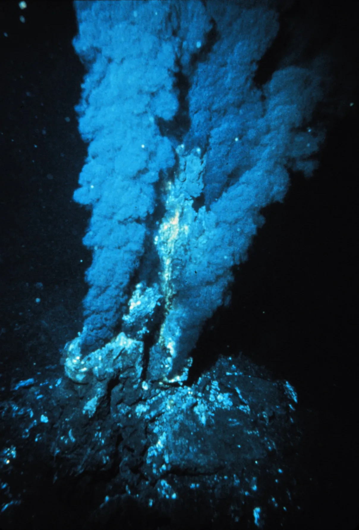 A hydrothermal vent chimney venting mineral-rich water on the dark seafloor