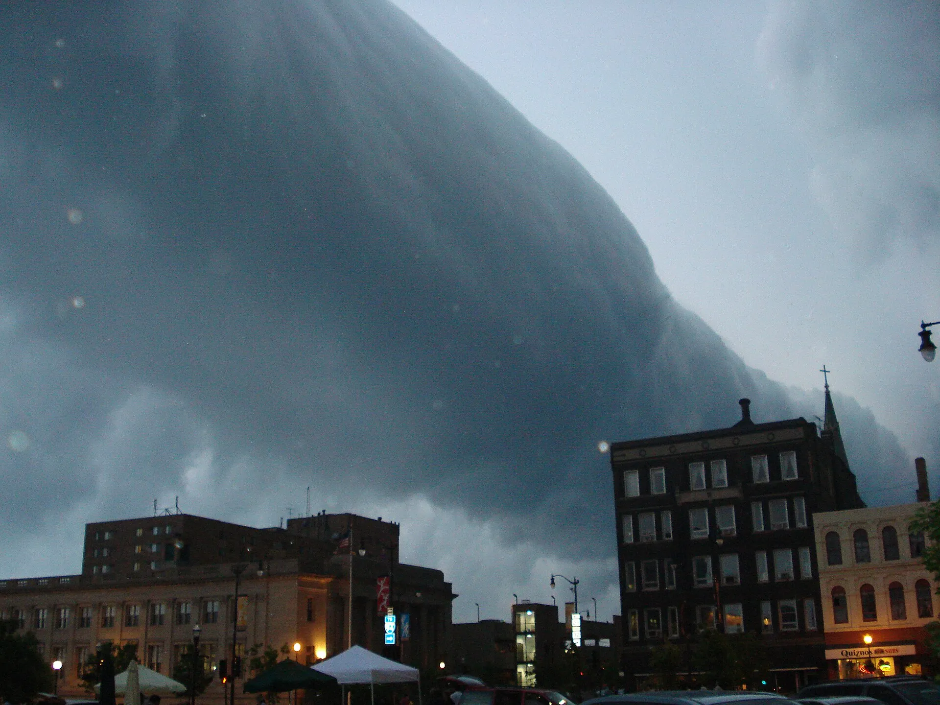 Long roll cloud sweeping low over rooftops ahead of a storm
