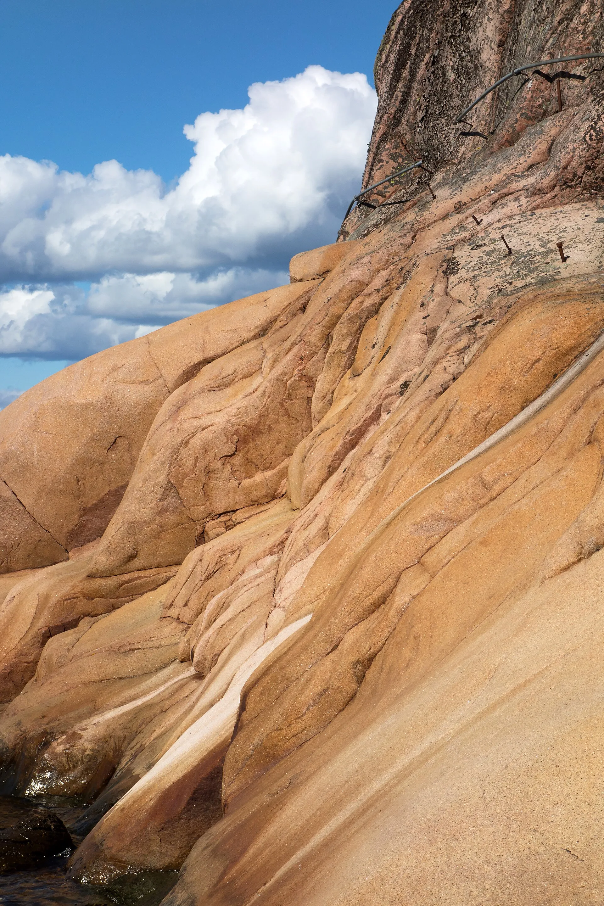 Bare granite outcrop rising under a bright cloudy sky