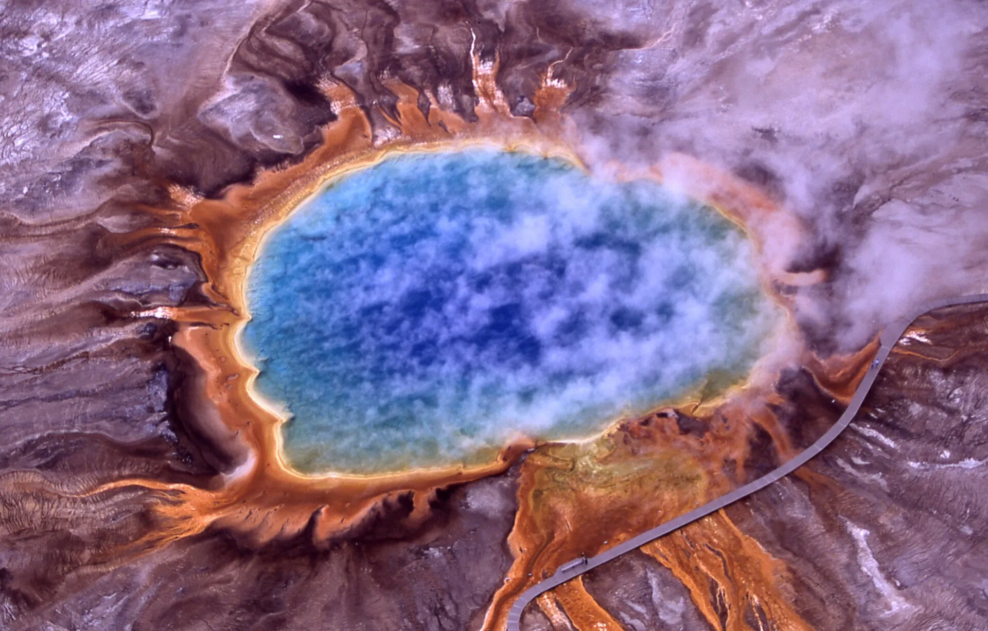 Vivid blue hot spring ringed with orange mineral terraces
