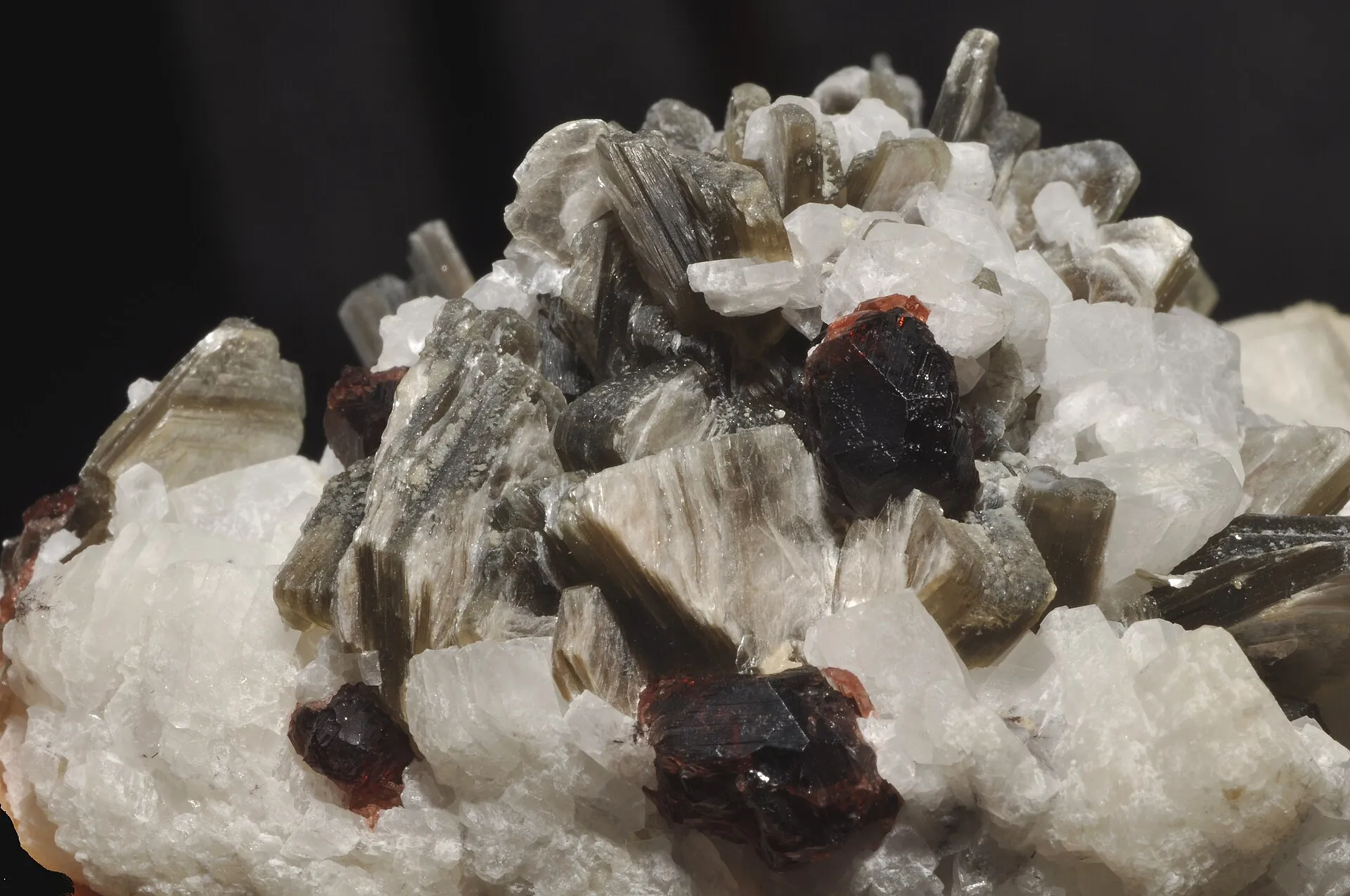 Silvery mica crystal sheets clustered with white quartz and red garnet