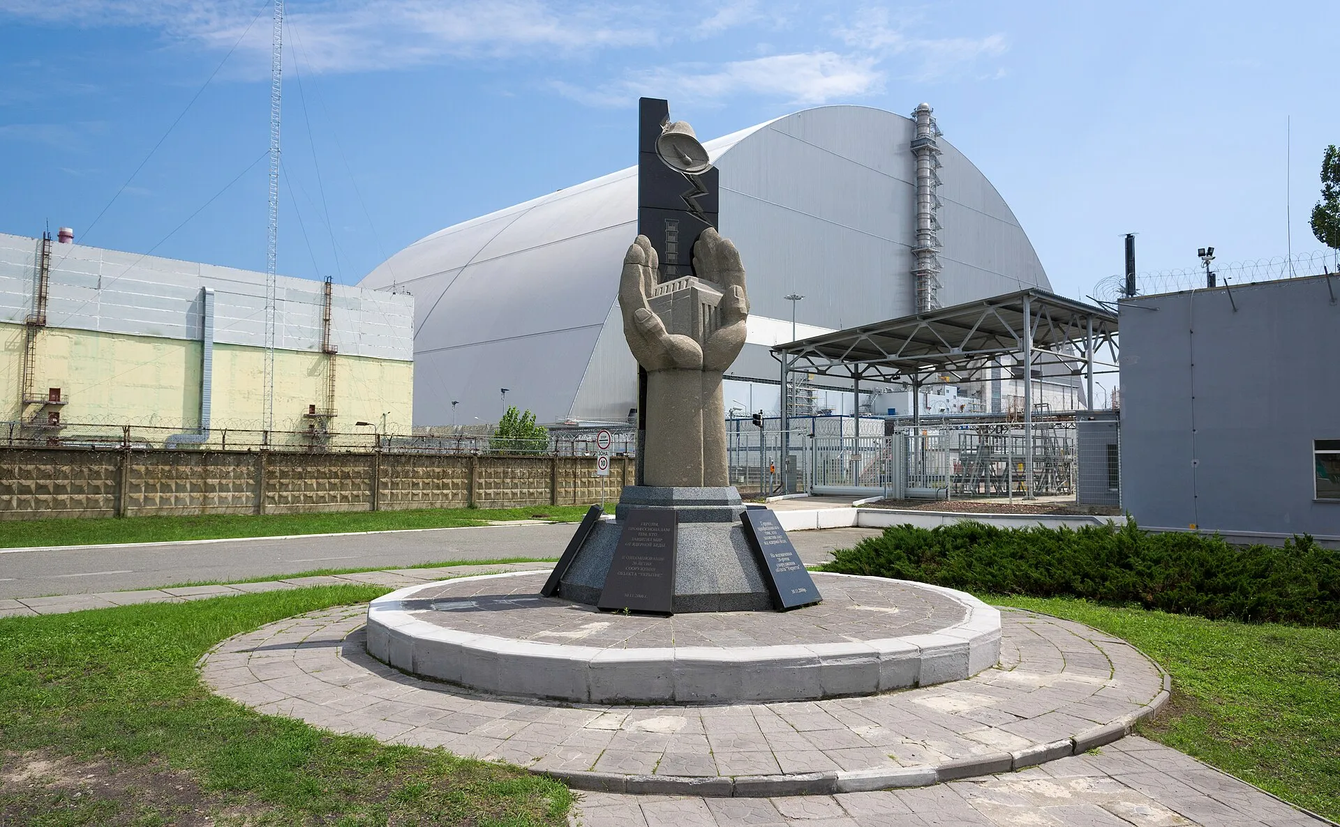 Memorial statue in front of the arched confinement shelter at Chernobyl