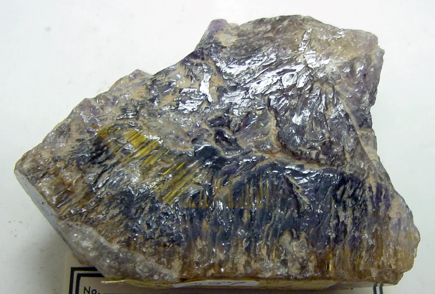 Rough mineral specimen streaked with metallic blue crystals