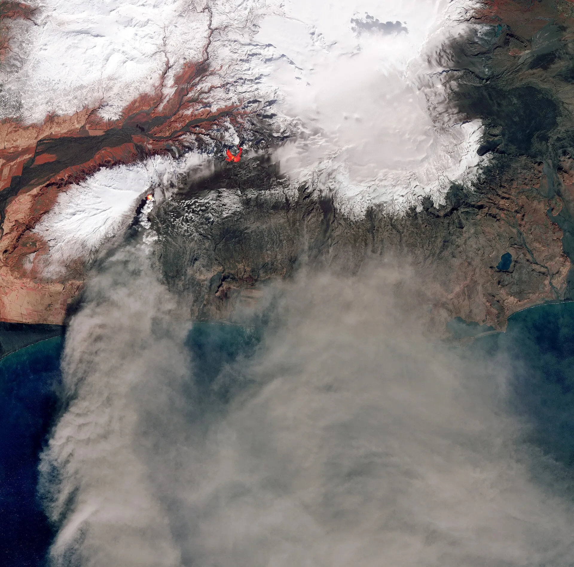 Satellite view of a volcanic eruption melting through a glacier's ice cap