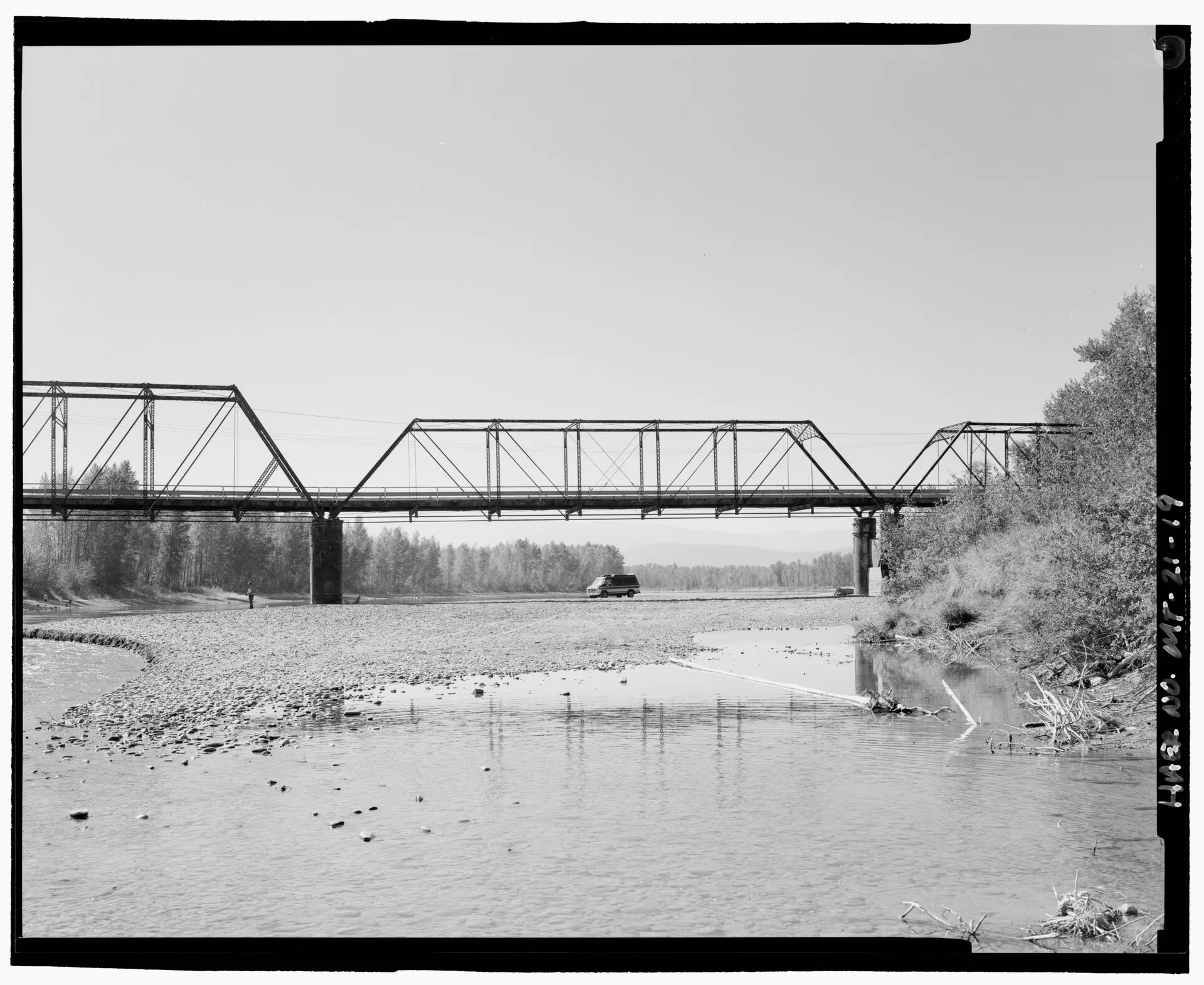 Side view of a steel through-truss bridge spanning a river