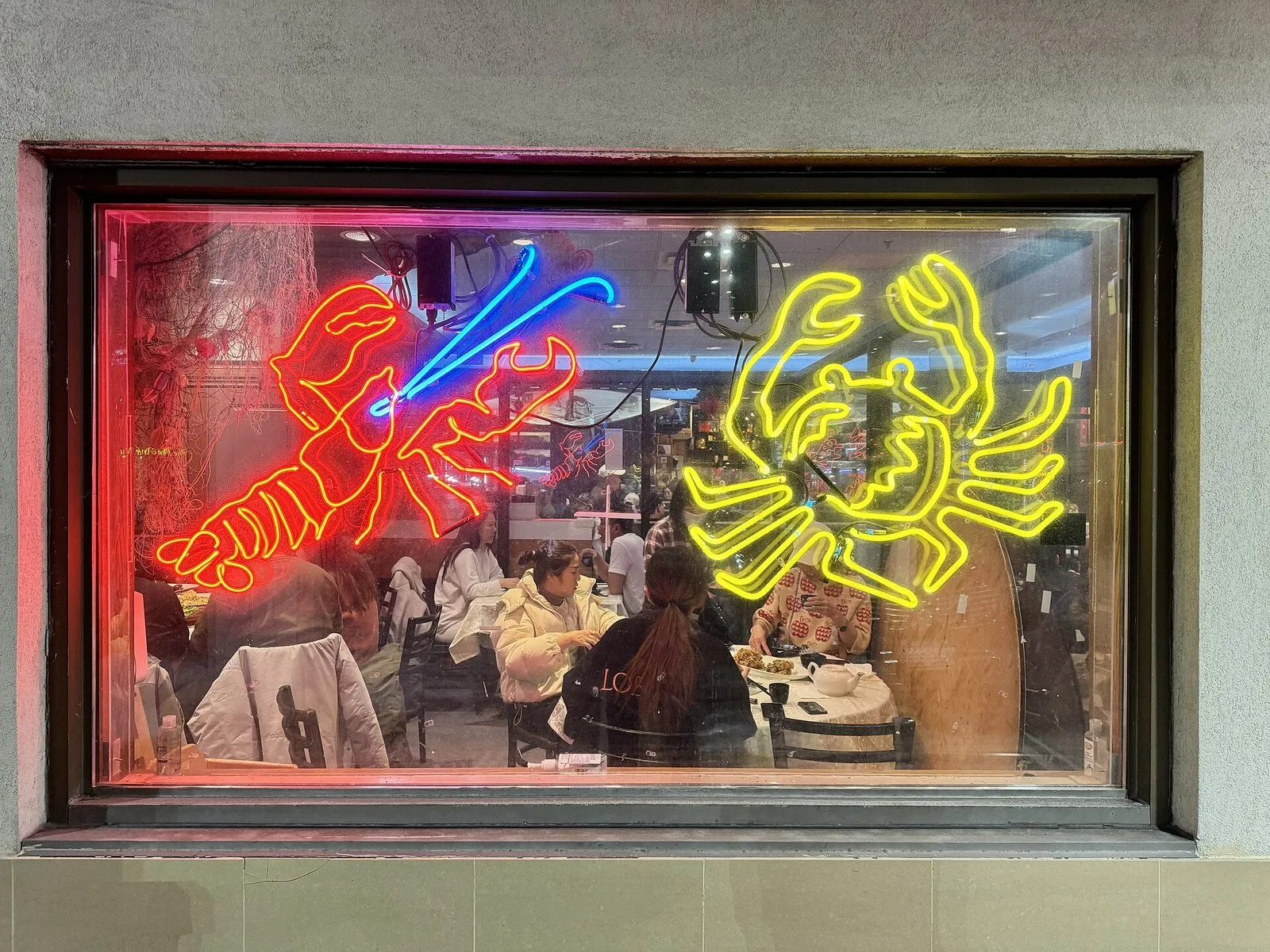 Red lobster and yellow crab neon signs glowing in a restaurant window