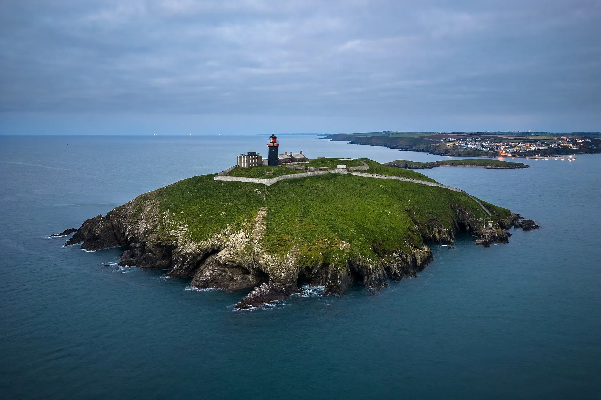 Lighthouse standing on a small green island surrounded by the sea