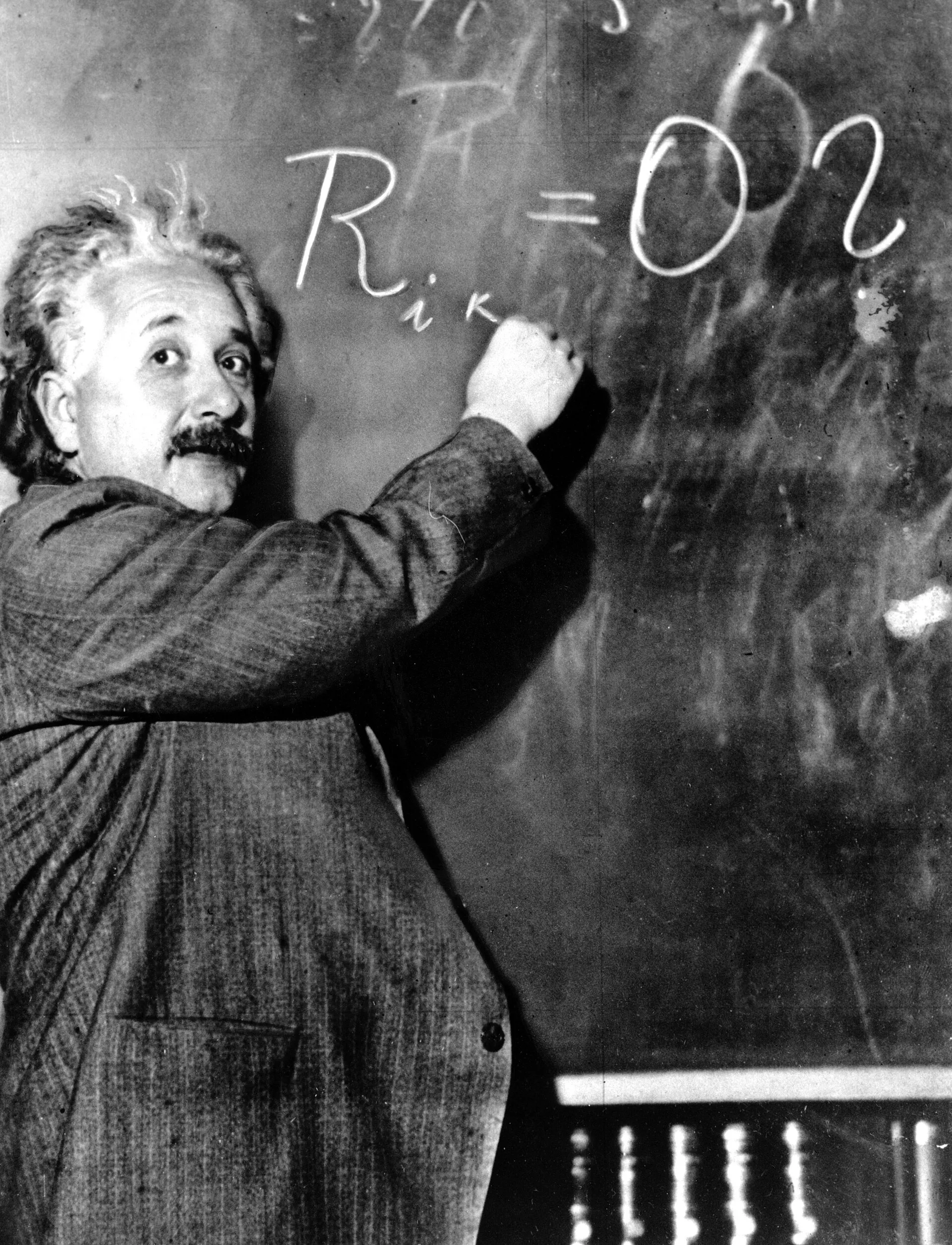 Albert Einstein writing equations on a blackboard