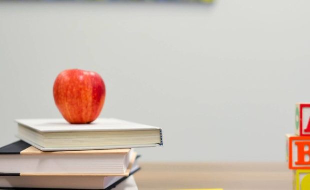 apples and books on a desk after a bachelor of science in education is earned